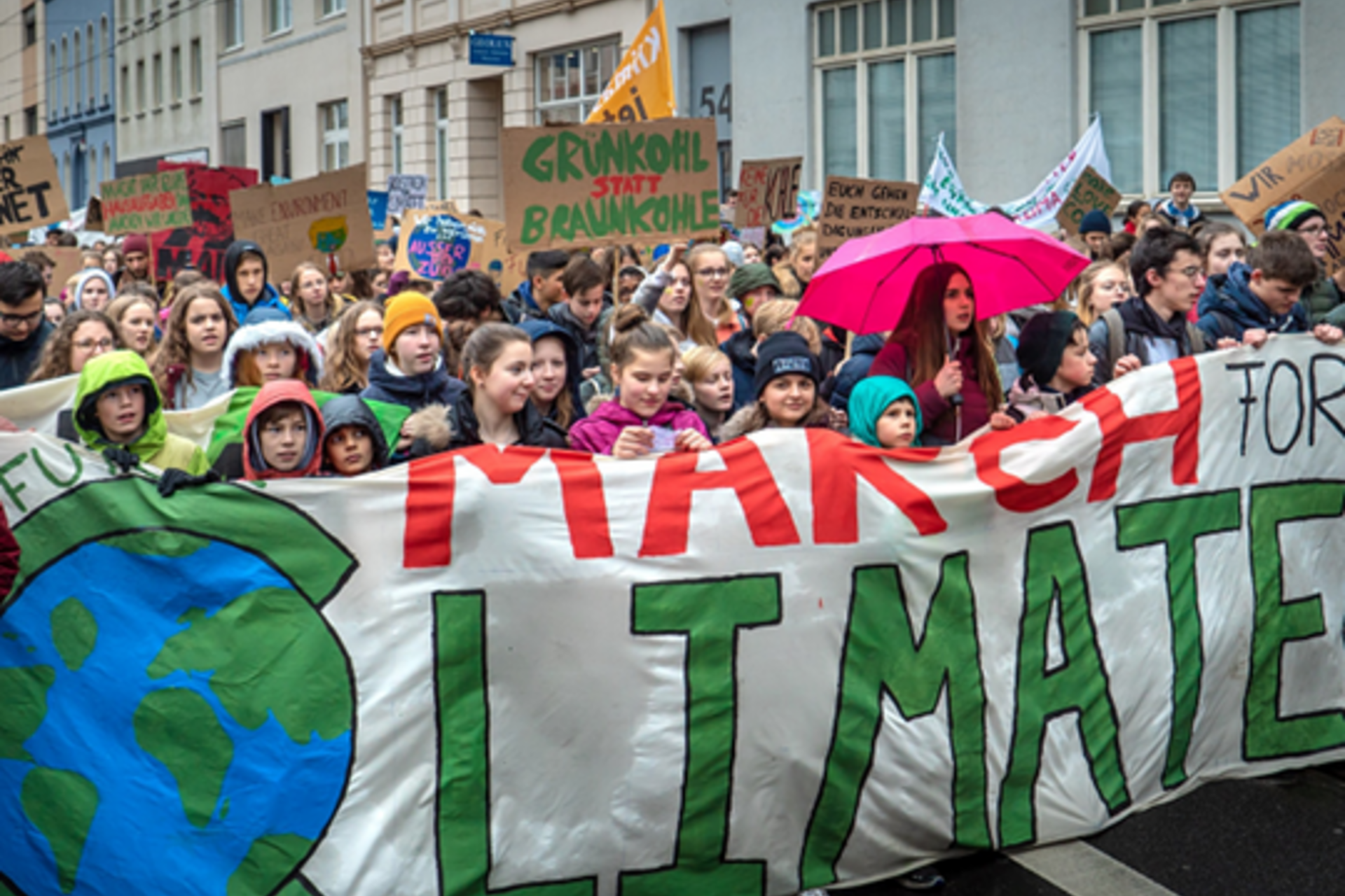 Climate change activists march down a street carrying banners and signs.