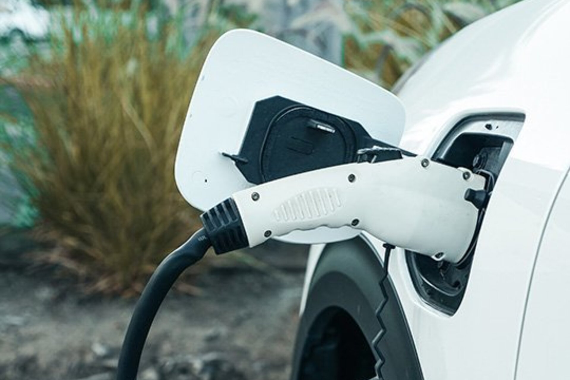 An electric car charger plugged in a white car