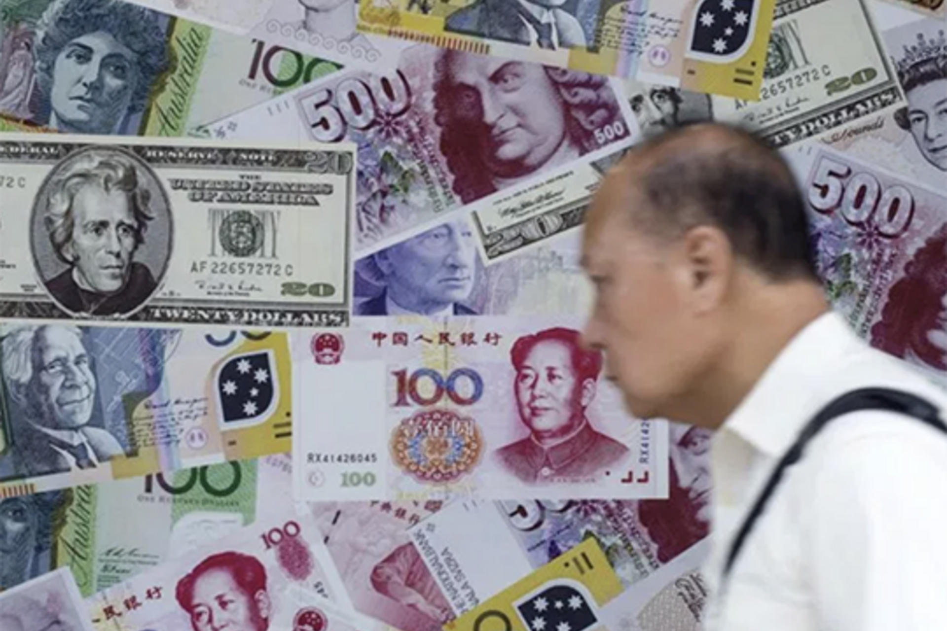 A man walks past an advertisement promoting China's renminbi (RMB) or yuan, U.S. dollar and Euro exchange services at foreign exchange store in Hong Kong, China.