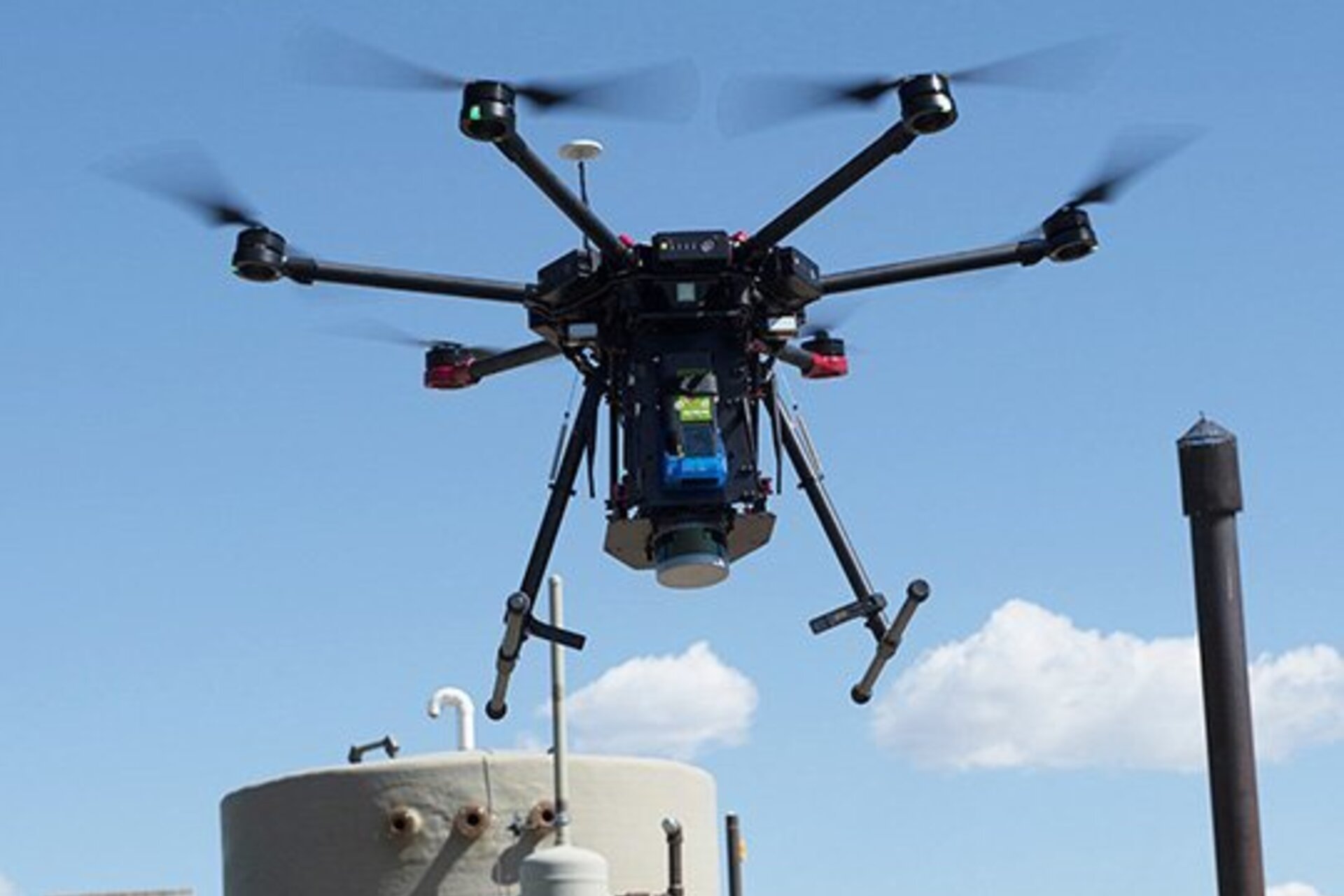 A drone hovering in the air near a tank of methane