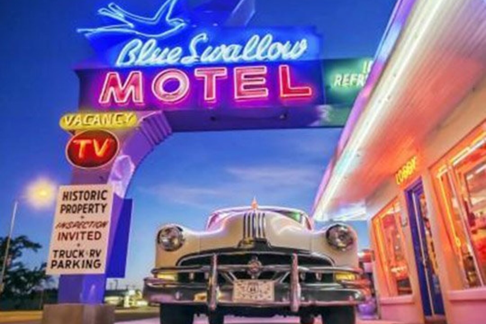 An old car at the Blue Swallow Motel, illuminated by neon and incandescent lights
