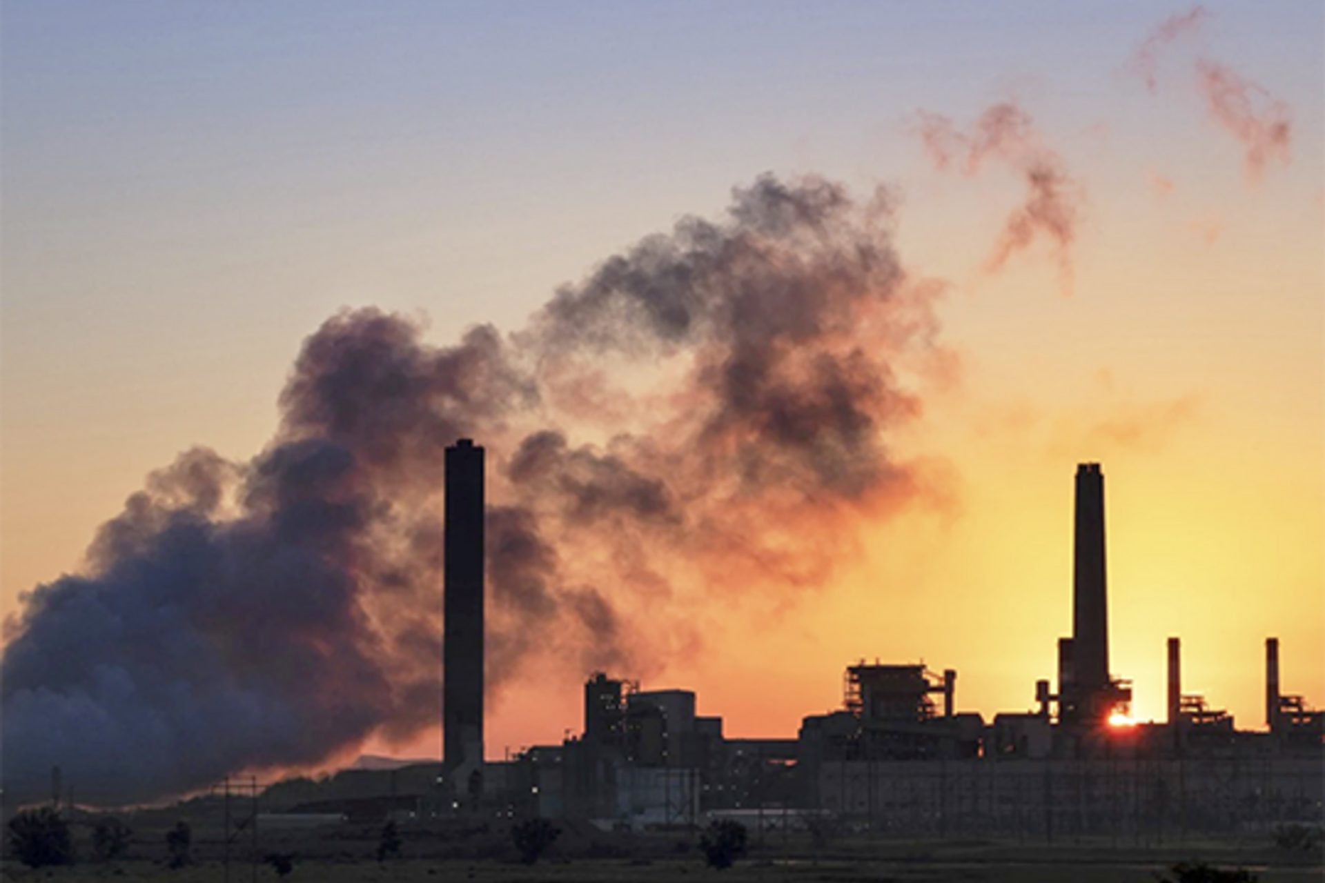 An energy plant silhouetted against a rising sun