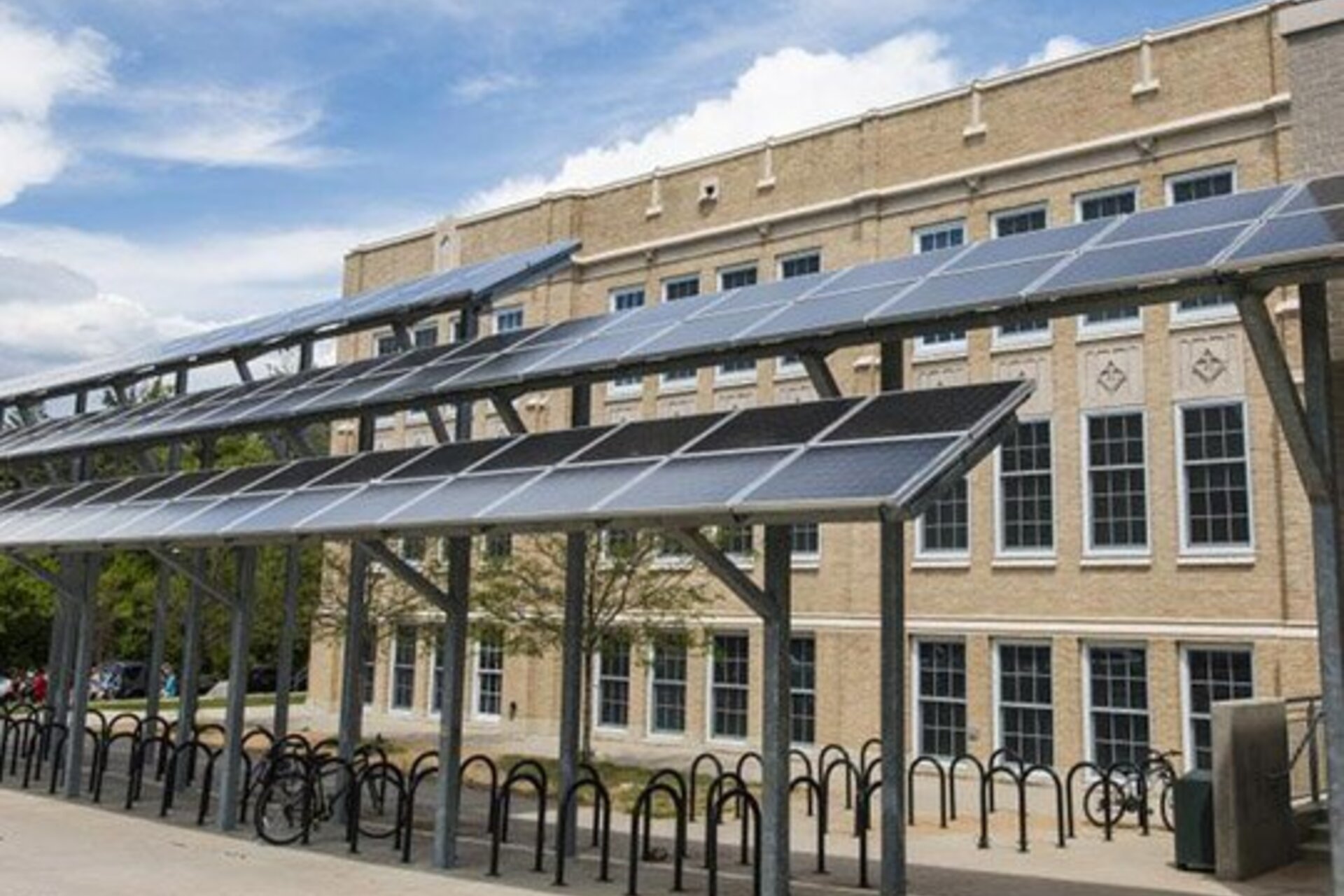 Solar panels on poles in front of a school providing shade over a walkway