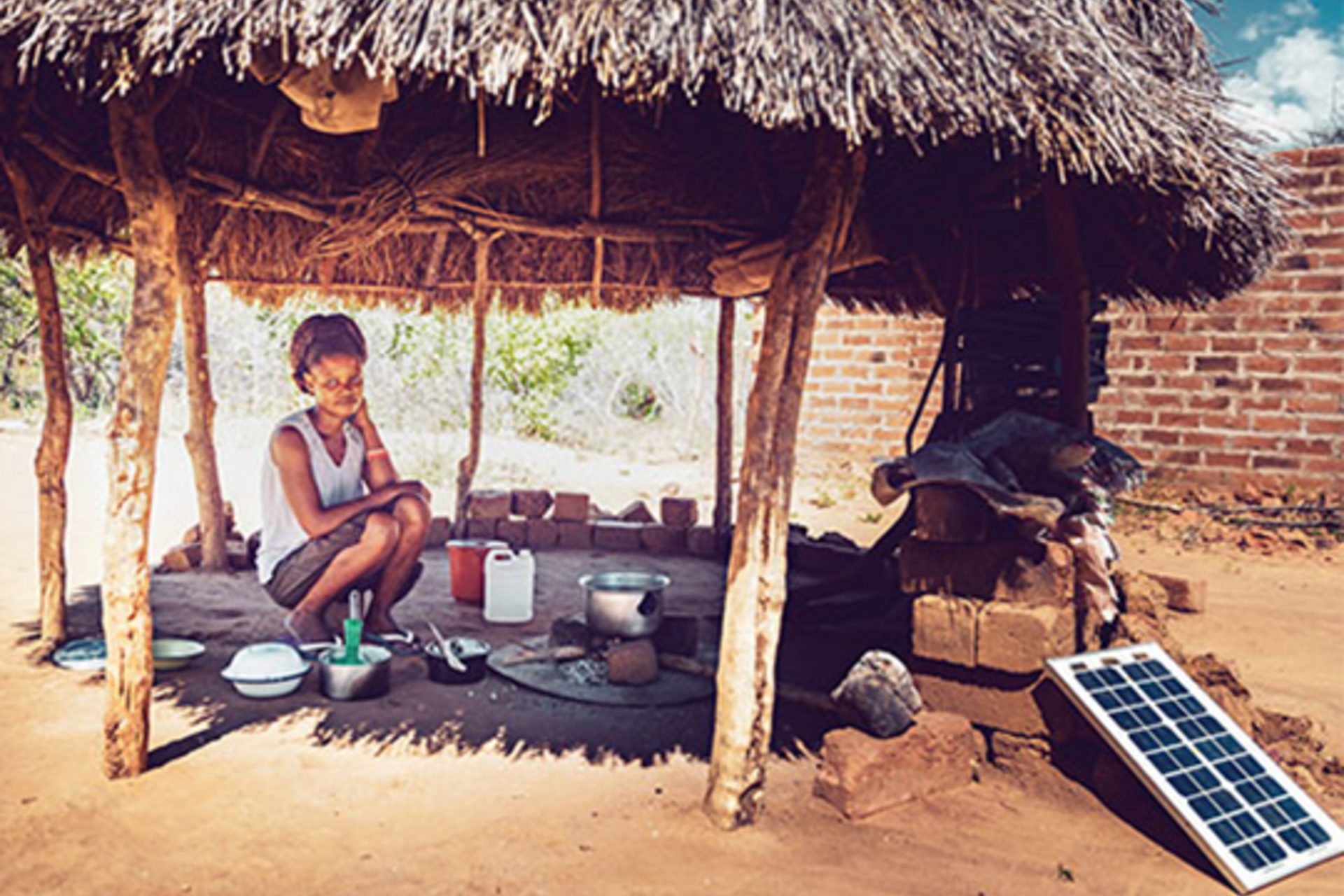 A young women cooking corn maze under a hut with a solar-powered stove