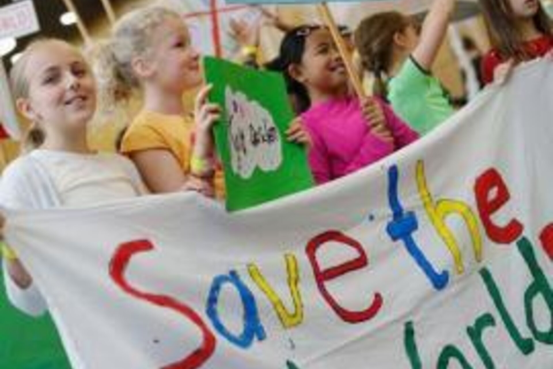 Kids smiling and holding a banner that says "Save the World" in primary colors