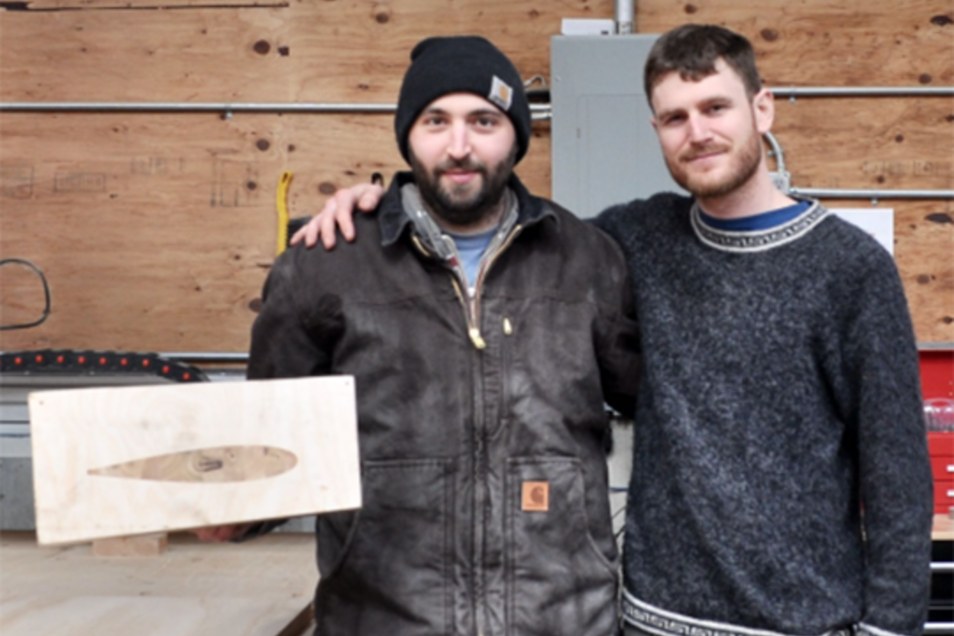 XFlow Energy co-founders Ian Brownstein, PhD ’18, and Ben Strom hold up a cross-sectional model of a wind turbine blade in their machining shop.