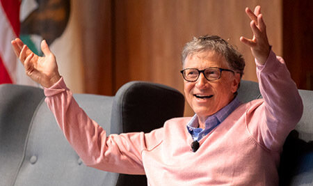 Bill Gates gives talk with arms in air on stage