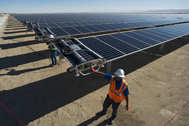 Workers attending to on ground solar panels