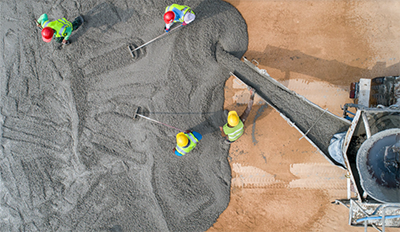 bird's eye of workers in safety equipment as they spread cement being poured from a cement truck